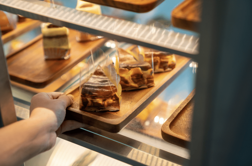 Hand placing pastries in a display case at restaurant